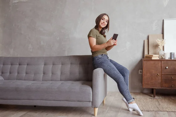 Mujer con auriculares mientras está sentado en el sofá en la habitación — Foto de Stock