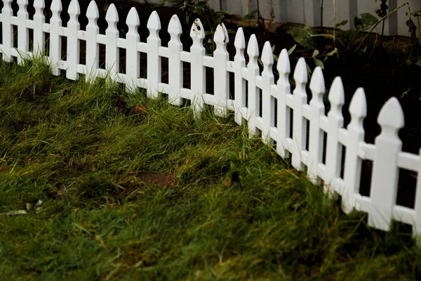 Plastic decoratieve kleine omheining voor een bloembed op een persoonlijk perceel. — Stockfoto