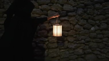 Koyu renk elbiseli bir adam ve yürüyen ve arayan bir fener. 