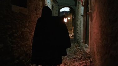 Koyu renk elbiseli bir adam ve yürüyen ve arayan bir fener. 