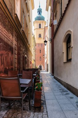 Varşova, Polonya - 19 Temmuz 2018: Varşova, Polonya'nın eski şehir. Dar sokak kafe tablolar ve çan kulesi Sain Martin Kilisesi.