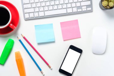 Klavyesi, faresi, not defteri, kalemi, boş ekranlı akıllı telefonu ve kahvesi olan modern beyaz ofis masası. Kopya saplı üst görünüm. İş ve strateji modeli..
