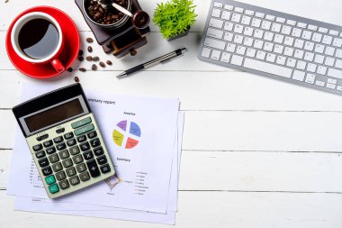 Klavye, kalem, hesap makinesi, finansal veri ya da grafik ya da tablo ve bir fincan kahveli Modern White ofis masası. Kopya alanı olan üst görünüm. Çalışma masası konsepti.