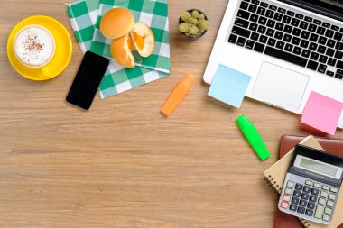 Dizüstü bilgisayarı, not defteri, hesap makinesi, akıllı telefon, fırın ve kahve ile ofis malzemeleri. Telif alanı olan üst görünüm..