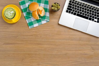 Dizüstü bilgisayarlı ofis masası, fırın ve bir fincan yeşil çay. Kopya alanı olan üst görünüm..