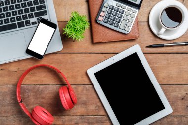 Bilgisayarlı masa masası, akıllı telefon, bir fincan kahve, kalem, kulaklık, hesap makinesi, tablet ve defter. Masada üst düzey ofis malzemeleri ve aletler. Çalışma masası konsepti..