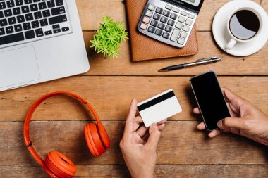 Akıllı telefonu tutan ve online alışveriş için kredi kartı kullanan bir adam. İnternetten alışveriş konsepti.