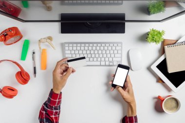 Akıllı telefonu tutan ve online alışveriş için kredi kartı kullanan bir adam. İnternetten alışveriş konsepti.