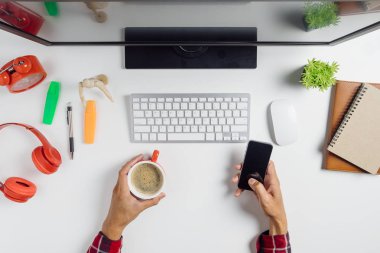 Erkek elleri boş ekrana dokunuyor. Akıllı bir telefon ve çalışma alanında bir fincan kahve tutuyor. Ürün gösterimi için tarama.