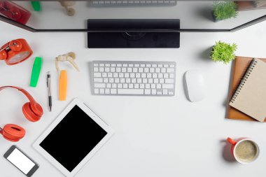 Bilgisayarlı ofis eşyaları, boş ekran akıllı telefon, kulaklık, not defteri, tablet ve kahve. Kopya alanlı üst görünüm. Çalışma masası konsepti..