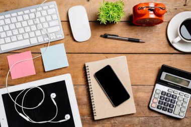 Klavye, fare, not defteri, kulaklık, kalem, defter, hesap makinesi, akıllı telefon ve kahve ile ofis malzemeleri. Kopyalama alanı olan üst görünüm. Çalışma masası konsepti.