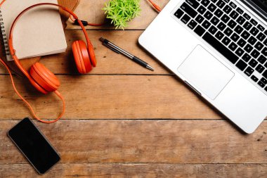 Bilgisayarlı masa masası, akıllı telefon, kalem, kulaklık ve not defteri. Düz konum fotoğrafı. Fotokopi alanı olan üst görünüm..
