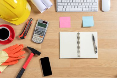 Bilgisayarlı, defterli, hesap makineli ofis masası, bir fincan kahve ve mühendis teçhizatı. Fotokopi alanı olan üst görünüm. Arkaplan inşa projesi fikri.