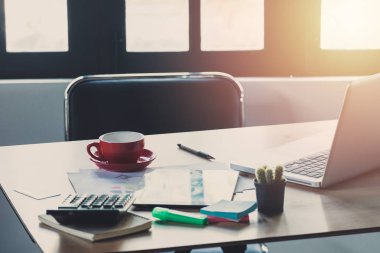 Dizüstü bilgisayarı olan işyeri ofis pencerelerinde rahat çalışma masası ve güneş parlaması.