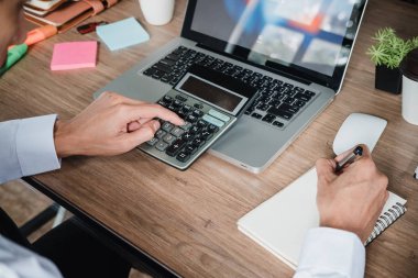 İş adamı, finansal veriler ve hesap makinesiyle modern ofisin beyaz masasında çalışıyor. İş analizi ve strateji kavramı.