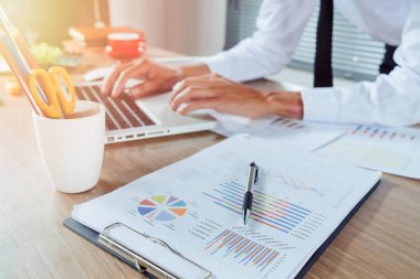 İş adamı, finansal veriler ve hesap makinesiyle modern ofisin beyaz masasında çalışıyor. İş analizi ve strateji kavramı.