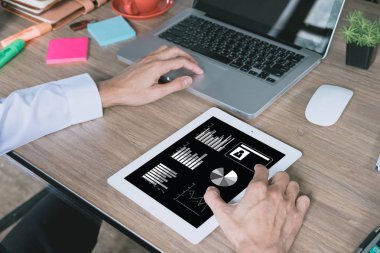 Modern ofisin ahşap masasında dijital tablet, kitap ve belgeyle çalışan işadamı. İş analizi ve strateji kavramını inceleyin..