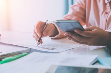 İş kadını akıllı telefon ve bilgisayar ekranındaki finansal verileri analiz ediyor. Kapat