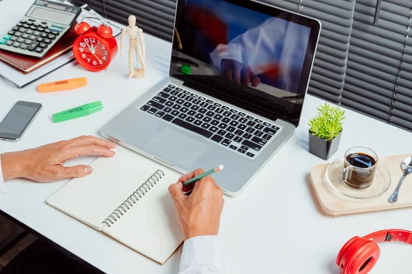 Ofis masasına not defteri yazan iş adamı elleri. Kapatın. İş konsepti.