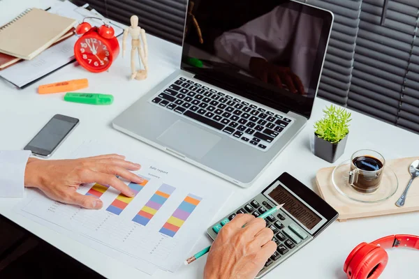 İş adamı, mali veriler ve hesap makinesiyle modern ofisteki wihite masasında çalışıyor. İş analizi ve strateji kavramı.