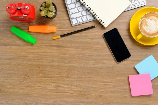 Klavye, not defteri, not defteri, kalem, saat, akıllı telefon ve bir fincan kahveli ofis masaüstü. Telif alanı olan üst görünüm.