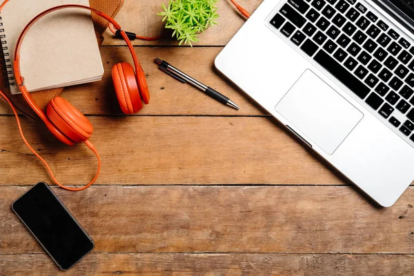 Bilgisayarlı masa masası, akıllı telefon, kalem, kulaklık ve not defteri. Düz konum fotoğrafı. Fotokopi alanı olan üst görünüm..