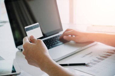 İş adamı elinde bir kredi kartı tutuyor ve online alışveriş için akıllı telefon kullanıyor. İnternetten alışveriş kavramı..
