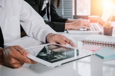 İki meslektaş masadaki tablet ve yeni modern bilgisayar laptopuyla verileri tartışıyor. İş ekibi analizi ve strateji kavramını kapat.