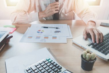 Dijital tablet bilgisayar, akıllı telefon ve dizüstü bilgisayarla çalışan bir iş adamı. Ahşap masa üzerinde finansal iş stratejisi katmanı etkisi olan bir bilgisayar.