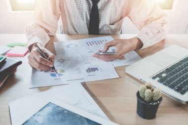 Akıllı telefon ve finansal veriler ve dizüstü bilgisayarla çalışan bir iş adamı ofisteki modern beyaz masada. İş analizi ve strateji kavramı.