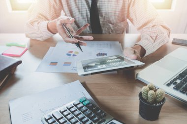 Modern ofiste dijital tablet, kitap ve belgelerle çalışan bir işadamı. İş analizi ve strateji kavramı.