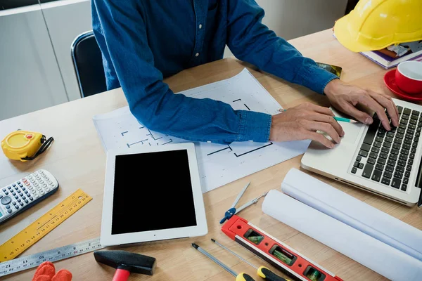 İşadamı, ofisteki inşaat alanında tablet ve dizüstü bilgisayarla mimari proje üzerinde çalışıyor..