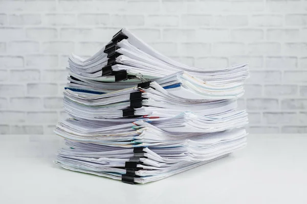 Stacks of business paper files on white desk, business report papers, piles of unfinished documents.Business concept