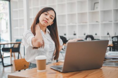 Stresli bir ofis çalışanı, masasında dinlenmek ve esnemek için biraz zaman ayırır..