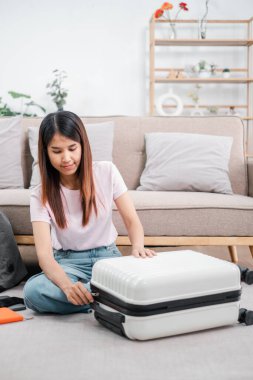 Genç bir kadın şık bir oturma odasında bavulunu toplayarak yerde oturuyor. Seyahat macerasına ya da tatile hazırlanıyor..