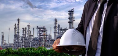 Mühendis bir kask büyük sanayi arka plan üzerinde tutuyor. Sanayi arka plan üzerinde inşaat müdürü.