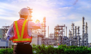 Mühendis büyük bir endüstri arka planında duruyor. Sektörün arka planında inşaat yöneticisi.