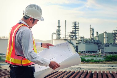 Mühendis büyük bir endüstri geçmişinin planını kontrol ediyor. Sektörün arka planında inşaat yöneticisi.