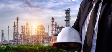 Mühendis bir kask büyük sanayi arka plan üzerinde tutuyor. Sanayi arka plan üzerinde inşaat müdürü.