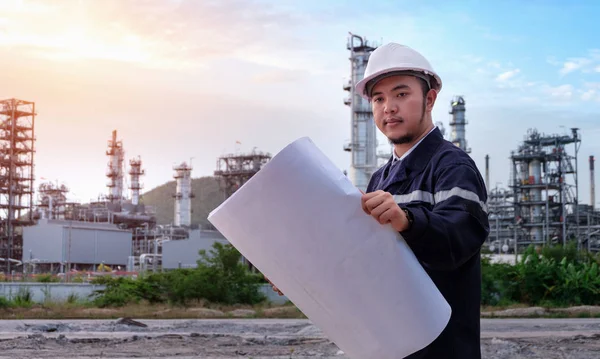 Mühendis büyük bir endüstri geçmişinin planını kontrol ediyor. Sektörün arka planında inşaat yöneticisi.