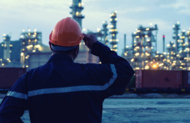 Mühendis, büyük sanayi arka plan üzerinde duruyor. Bokeh Sanayi ışık ile zaman akşam içinde sanayi arka plan üzerinde inşaat müdürü.