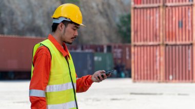 Mühendis konteyner sahasında Smart Phone üzerinde çalışıyor. Lojistik İthalat İhracat Şirketi Endüstriyel Konteynır Bahçesi.