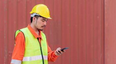 Mühendis konteyner sahasında Smart Phone üzerinde çalışıyor. Lojistik İthalat İhracat Şirketi Endüstriyel Konteynır Bahçesi.