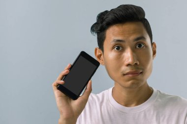 Asyalı adam cep telefonunu kullanmakta tereddüt ediyor.