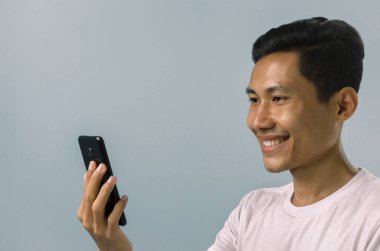 Cep telefonuna bakan Asyalı adam..