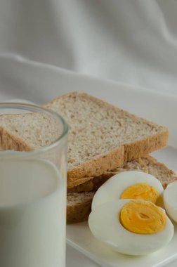 Kahvaltı için tam buğday ekmeği, haşlanmış yumurta ve süt..