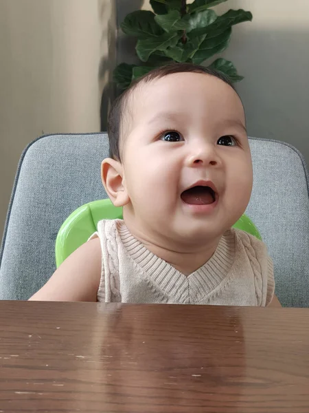 Asian baby laughing, Wow face sitting on a chair