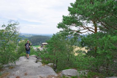Gezgin dağın tepesine tırmandı ve etrafına baktı, tepeden manzaranın tadını çıkardı.