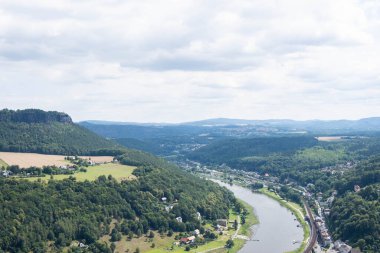 Elbe nehri, uzaktaki dağlar, nehir boyunca küçük kasabalar ve çeşitli ağaçlardan oluşan zengin bir orman..
