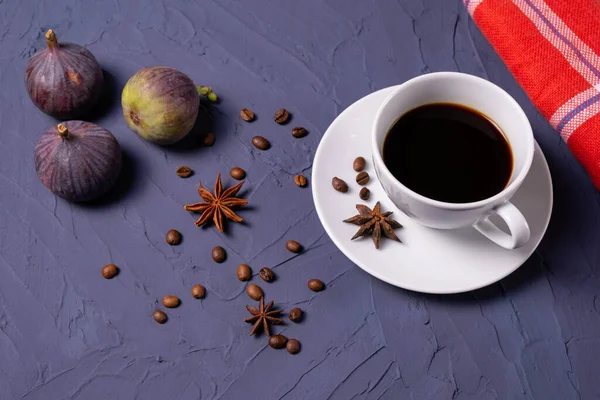 Bir fincan kahve, kahve çekirdeği, tarçın ve incir.